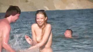 A mature woman sunbathes naked on the beach and plays with sand