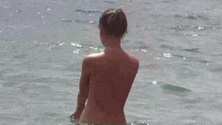 A group of nudists enjoy each other on the beach without clothes