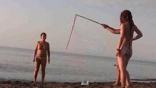 A naked girl is having fun on the beach, showcasing her body in a sensual way