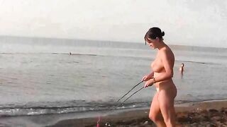 A naked girl is having fun on the beach, showcasing her body in a sensual way