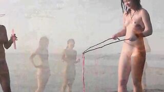 A naked girl is having fun on the beach, showcasing her body in a sensual way