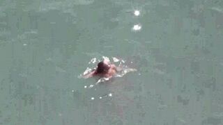 A pair of naked people are having fun at sea