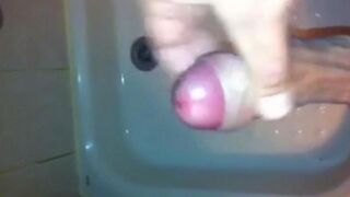 The kid masturbates his cock with his hand in the shower, trying not to cum