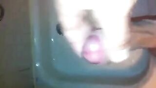 The kid masturbates his cock with his hand in the shower, trying not to cum