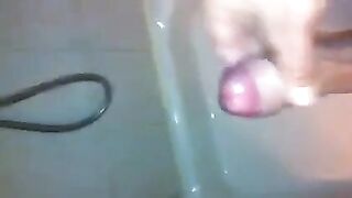 The kid masturbates his cock with his hand in the shower, trying not to cum