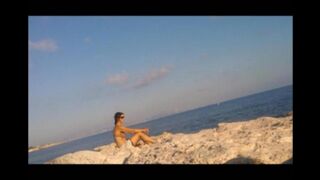 A girl is basking in sunbathing on the naked beach