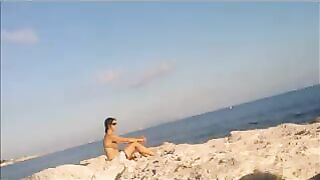 A girl is basking in sunbathing on the naked beach