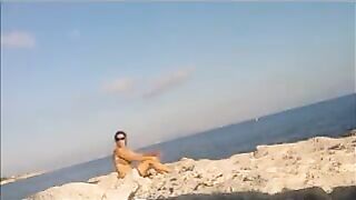 A girl is basking in sunbathing on the naked beach