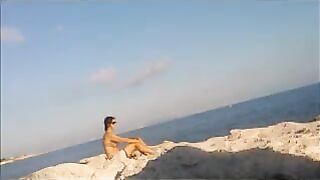 A girl is basking in sunbathing on the naked beach