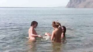 A group of nudists enjoy each other's company on the beach without clothes
